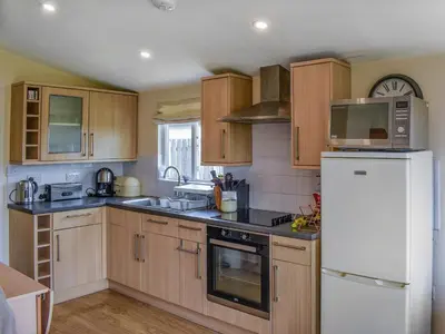 a kitchen with wooden cabinets and a white refrigerator at Seven Bays Retreat in Padstow