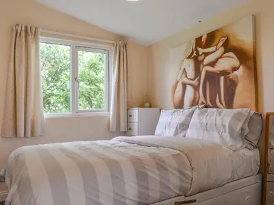 a bedroom with a bed with a painting on the wall at Seven Bays Retreat in Padstow