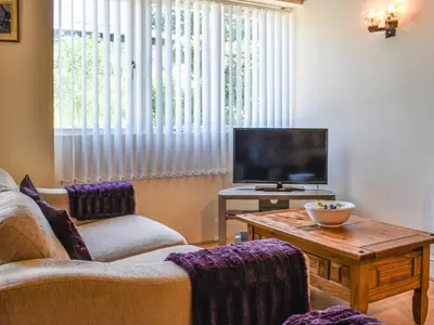a living room with a couch and a tv and a table at The Stable - Uk49829 in Callington