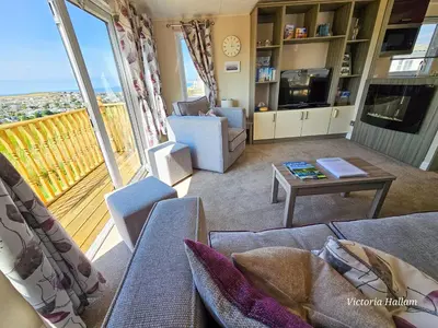 a living room with couches and a television and a balcony at Serenity in Truro