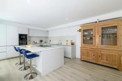 a kitchen with white counters and wooden cabinets at Luxury Apartment very close to Tolcarne Beach in Newquay