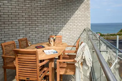 a wooden table and chairs on a balcony at Luxury Apartment very close to Tolcarne Beach in Newquay