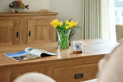 a vase of yellow tulips and a cup on a wooden table at Luxury Apartment very close to Tolcarne Beach in Newquay