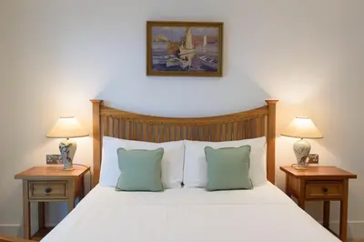 a bedroom with a white bed with two nightstands and two lamps at Luxury Apartment very close to Tolcarne Beach in Newquay