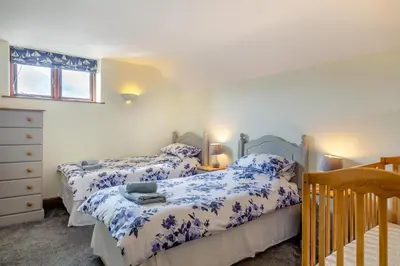 a bedroom with two beds and a crib at 3 Bed in St. Endellion oc-o30761 in Saint Endellion