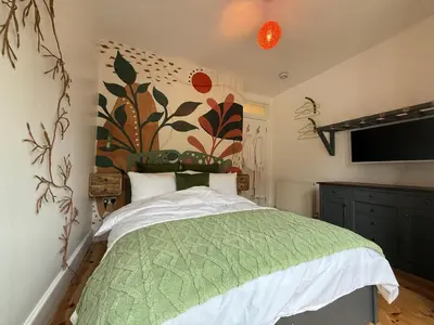 a bedroom with a bed with a green comforter at Seaweed Suite, secluded seaside stay with garden view in Newquay