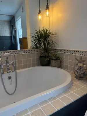 a bath tub in a bathroom with potted plants at Seaweed Suite, secluded seaside stay with garden view in Newquay
