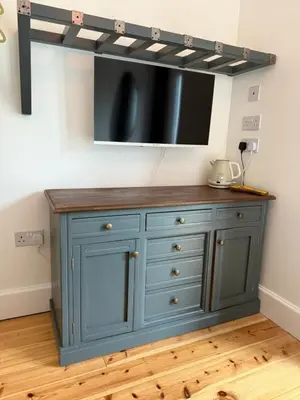 a blue cabinet with a tv on top of it at Seaweed Suite, secluded seaside stay with garden view in Newquay
