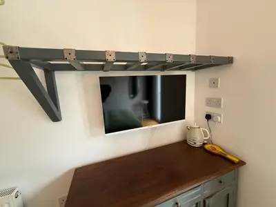 a shelf on the wall with a tv in a room at Seaweed Suite, secluded seaside stay with garden view in Newquay