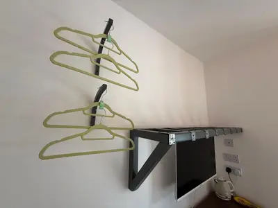 two green hoses hanging on a wall next to a tv at Seaweed Suite, secluded seaside stay with garden view in Newquay