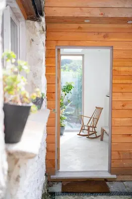 an open door to a patio with plants and chairs at Back Lane Cottage Cornwall in Gwinear