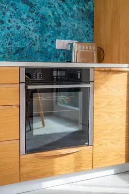 a kitchen with an oven in a wooden cabinet at Back Lane Cottage Cornwall in Gwinear