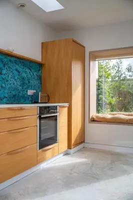 a kitchen with wooden cabinets and a window at Back Lane Cottage Cornwall in Gwinear