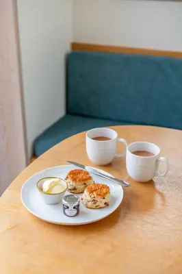 a plate with donuts and two cups of coffee on a table at Back Lane Cottage Cornwall in Gwinear