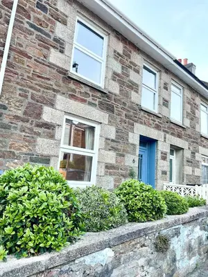 a brick house with a blue door and bushes at North Coast Hideaway in Redruth