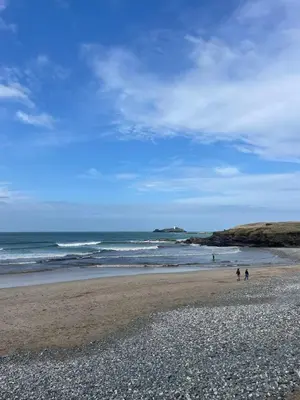 two people walking on a beach near the ocean at North Coast Hideaway in Redruth
