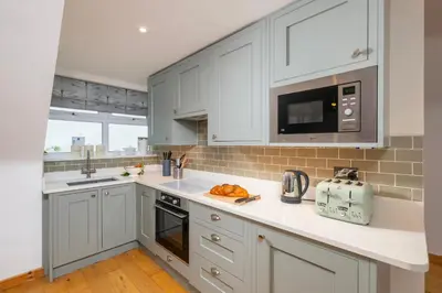 a kitchen with white cabinets and a counter top at Blue Mist Apartment in St Ives