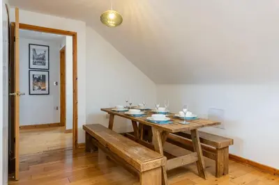 a dining room with a wooden table and benches at Blue Mist Apartment in St Ives