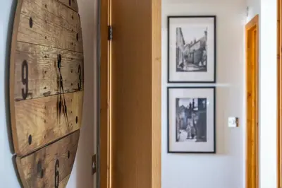 a surfboard hanging on a wall with framed pictures at Blue Mist Apartment in St Ives