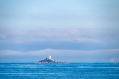 a lighthouse on an island in the middle of the ocean at Blue Mist Apartment in St Ives