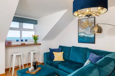 a living room with a blue couch and two stools at Blue Mist Apartment in St Ives
