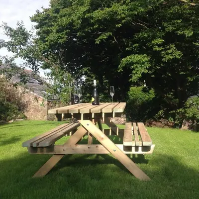 a picnic table with a bottle of wine on it at The Blacksmith's Shop in Port Isaac