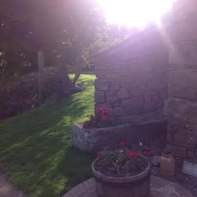 a garden with a stone wall and flowers in a yard at The Blacksmith's Shop in Port Isaac