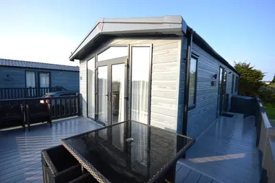 a small house with a glass table on a deck at Riverwood Lodge, Padstow in Padstow