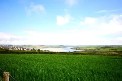 a field of green grass with a river in the background at Riverwood Lodge, Padstow in Padstow