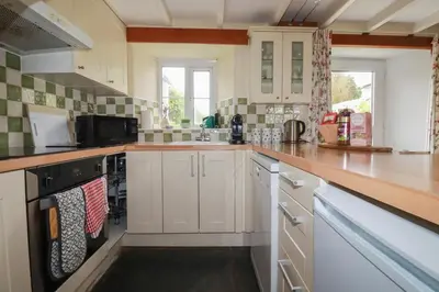 a kitchen with white cabinets and a counter top at Trevean in Bude