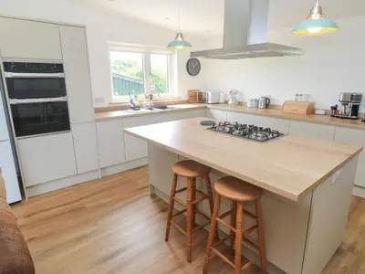 a kitchen with a island with a stove and stools at Swallows Nest in St Ives