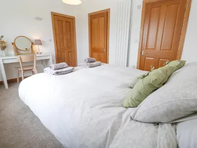 a large white bed in a room with a desk at Swallows Nest in St Ives