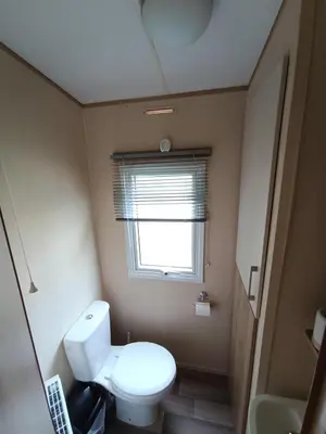 a small bathroom with a toilet and a window at The Green - Summer Breeze in Crantock