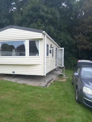 a white caravan with a car parked next to it at The Green - Summer Breeze in Crantock