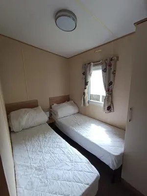 two beds in a small room with a window at The Green - Summer Breeze in Crantock