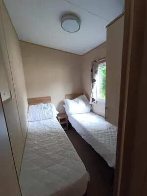 two beds in a small room with a window at The Green - Summer Breeze in Crantock