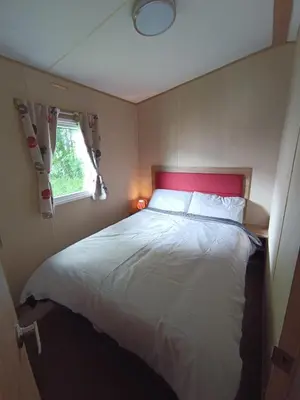 a bedroom with a white bed with a red headboard at The Green - Summer Breeze in Crantock