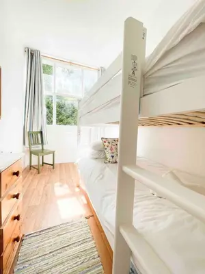 a bedroom with two bunk beds and a desk at Mermaid Apartment, A Colourful Coastal Escape By The Sea, Child Friendly in St Ives
