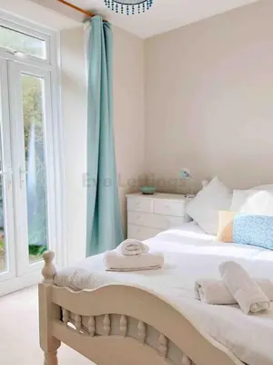 a bedroom with a bed with blue curtains and a window at Mermaid Apartment, A Colourful Coastal Escape By The Sea, Child Friendly in St Ives