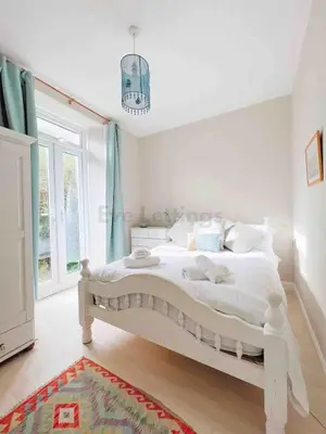a bedroom with a white bed with a chandelier at Mermaid Apartment, A Colourful Coastal Escape By The Sea, Child Friendly in St Ives