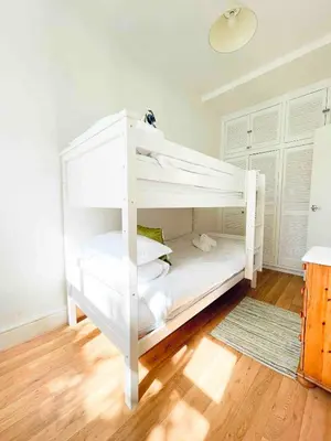 a white bunk bed in a room with wooden floors at Mermaid Apartment, A Colourful Coastal Escape By The Sea, Child Friendly in St Ives