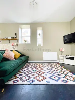 a living room with a green couch and a rug at Lisas Beach Pad, A Charming Coastal Retreat with Parking in St Ives