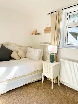 a bedroom with a white bed and a window at Lisas Beach Pad, A Charming Coastal Retreat with Parking in St Ives