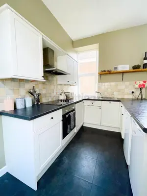 a kitchen with white cabinets and black counter tops at Lisas Beach Pad, A Charming Coastal Retreat with Parking in St Ives