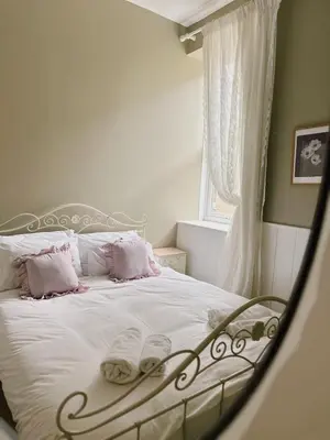 a bedroom with a bed with white sheets and pink pillows at Lisas Beach Pad, A Charming Coastal Retreat with Parking in St Ives