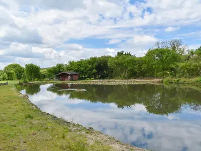 a pond with a house in the middle of it at The Old Workshop - Uk49871 in Lanivet