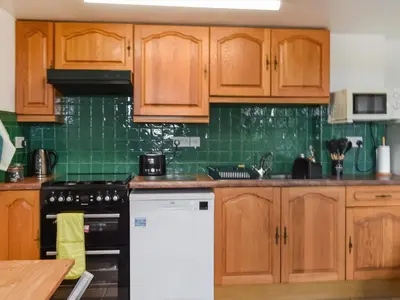 a kitchen with wooden cabinets and a stove top oven at The Old Workshop - Uk49871 in Lanivet
