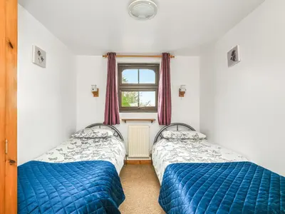 two beds in a room with a window at The Old Workshop - Uk49871 in Lanivet