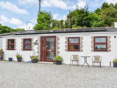 a white cottage with a table and chairs in front of it at Hosta House - Uk49872 in Lanivet