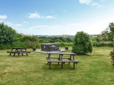 two picnic tables and a grill in the grass at Hosta House - Uk49872 in Lanivet